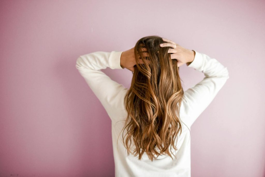 Woman touching her wavy brown hair, symbolising recovery from PCOS hair loss